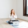 Katie sitting in a mindful pose in front of a laptop on a yoga mat