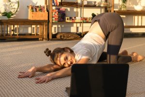 Person practicing puppy pose in front of a computer