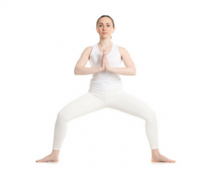 women in white outfit showing how squat pose is done