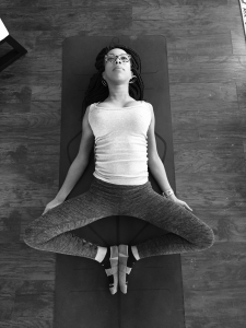 black and white on women laying on ground on her yoga mat stretching