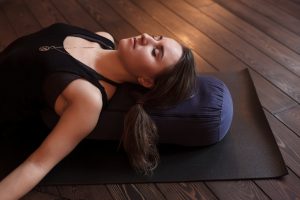 women laying on ground with pillow doing yoga poses