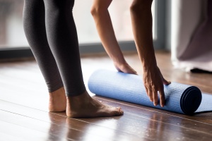 women rolling up mat after lesson learning yoga teaching tips