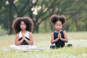 two girls taking a lesson from someone teaching children yoga