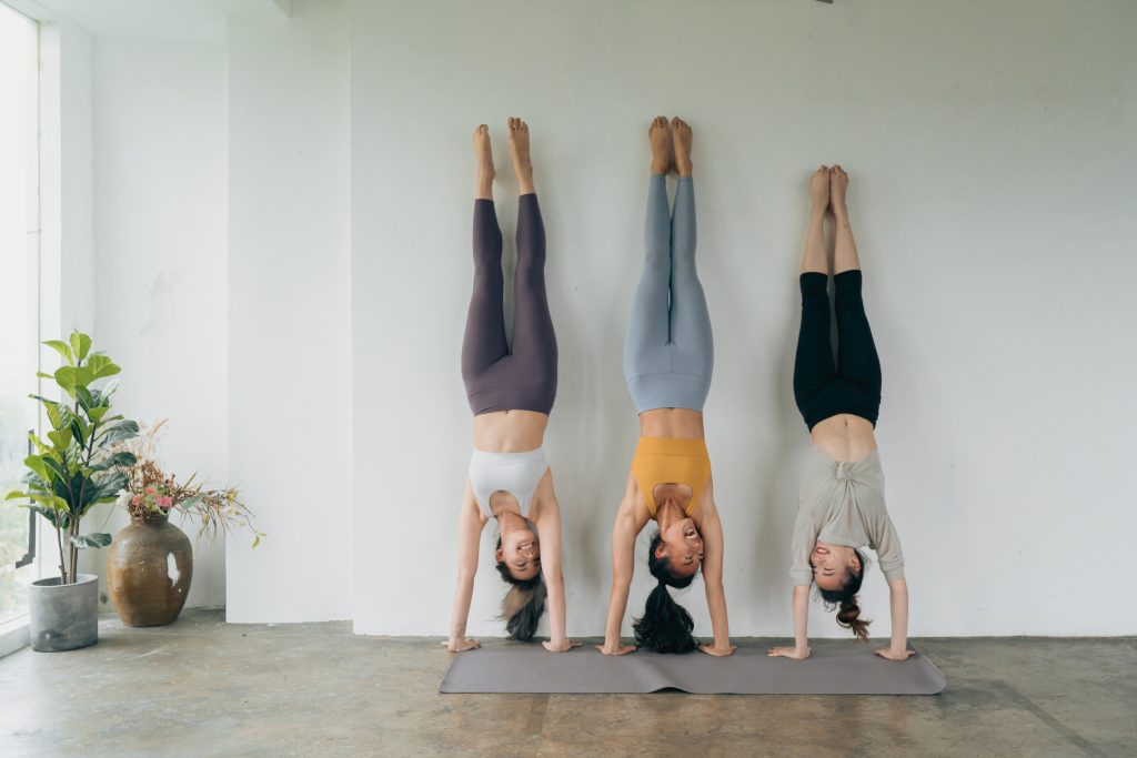 Three people doing handstand against the wall