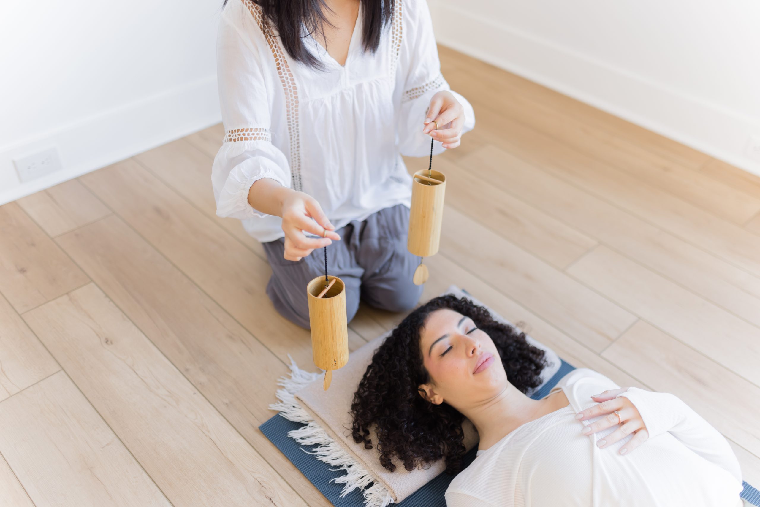 Shirley guiding a student through a sound bath - student laying on a yoga mat