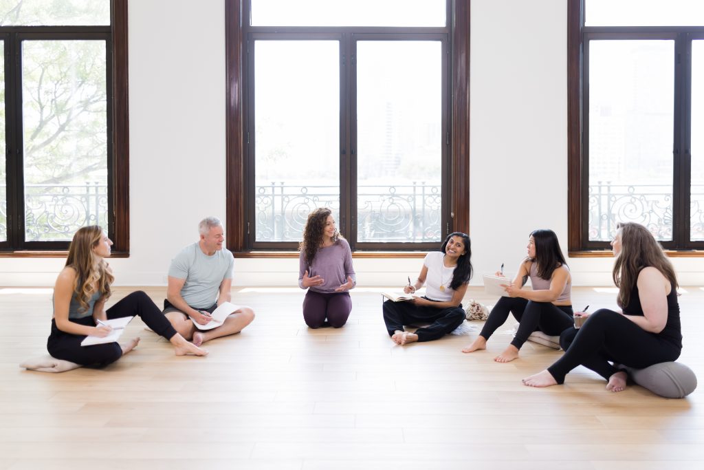 A group photo of YogaRenew's lead teachers conversing in a semi-circle