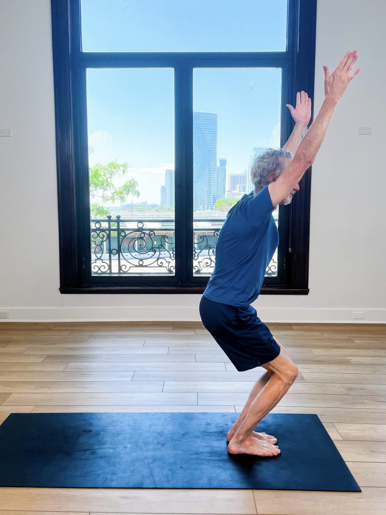 Man on a yoga mat doing chair pose