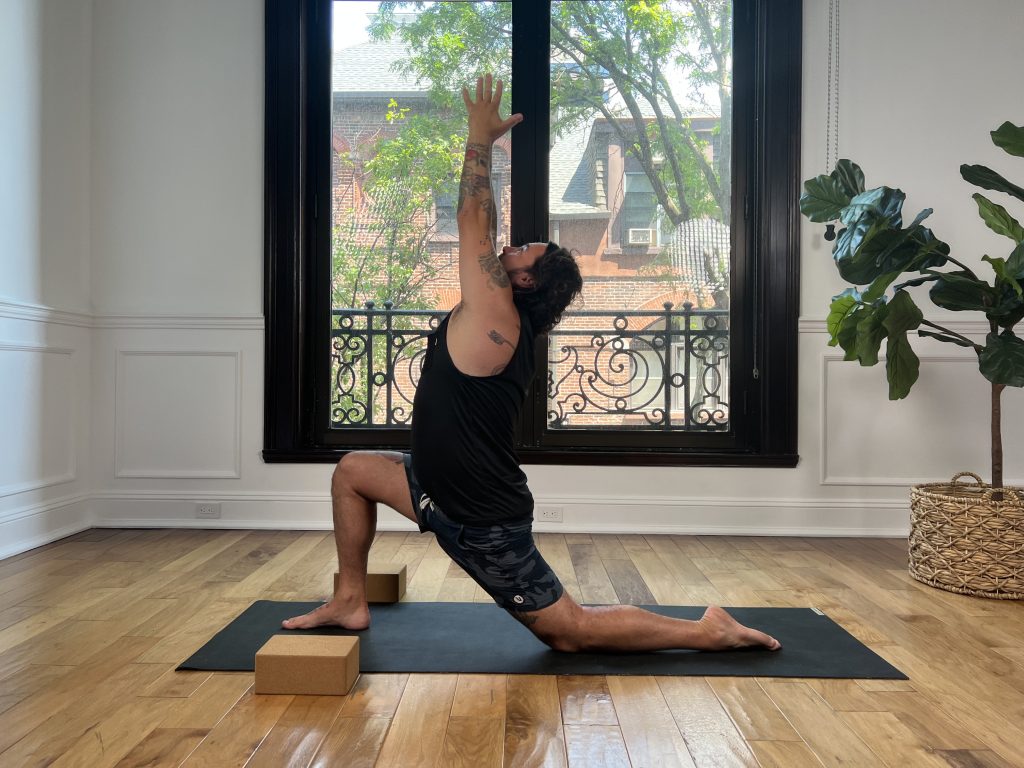 Man on a yoga mat in crescent lunge with two blocks