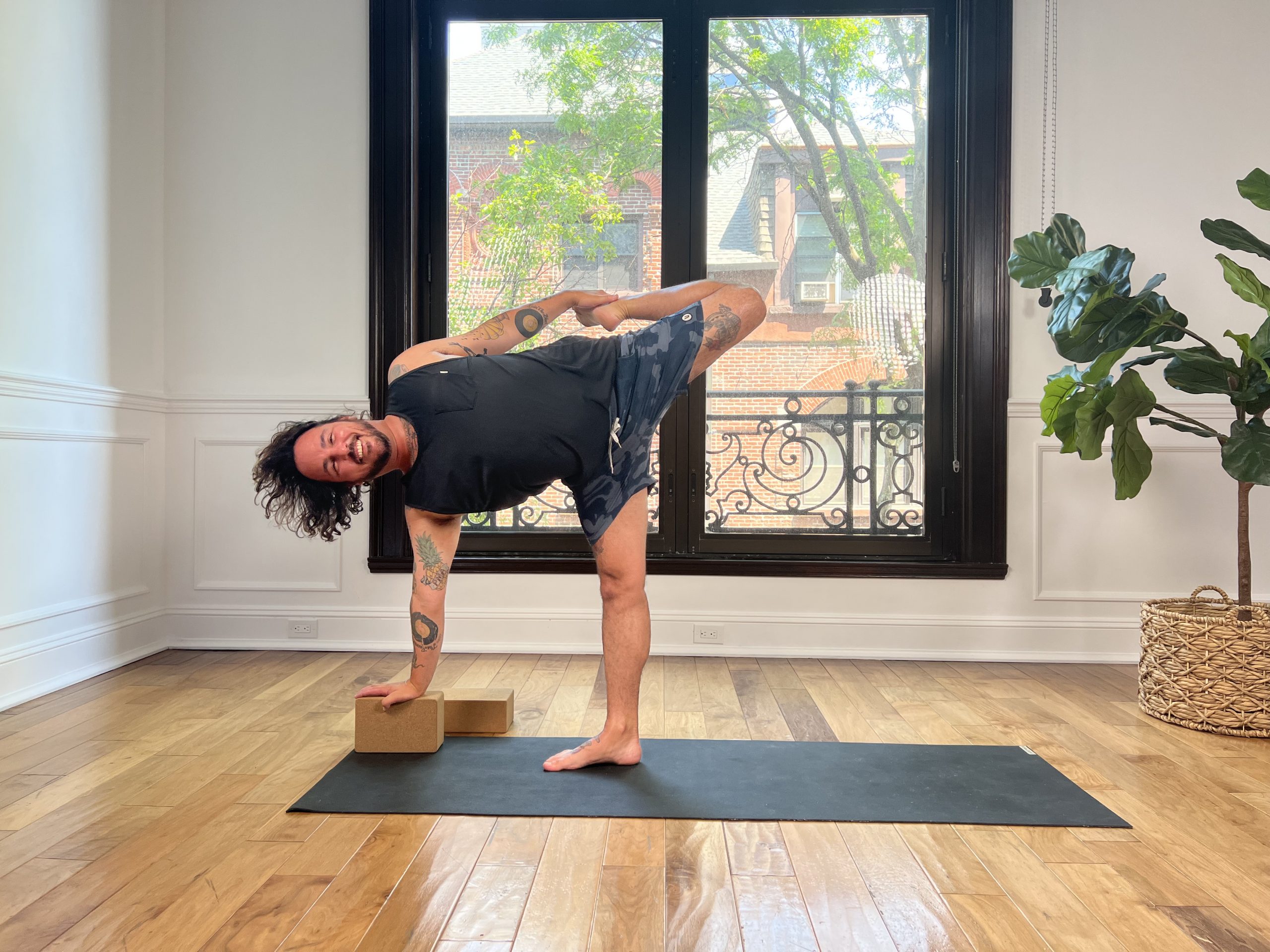 Man in half moon bow pose using one block for the arm reaching to the floor