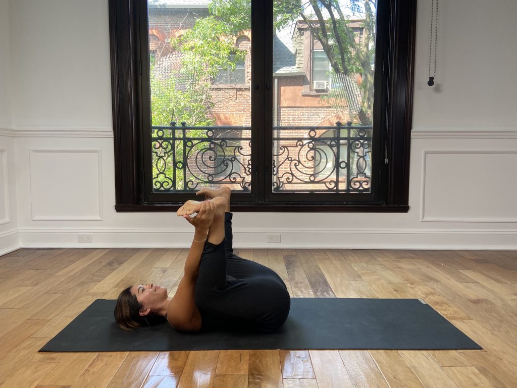 Girl in happy baby pose on a yoga mat