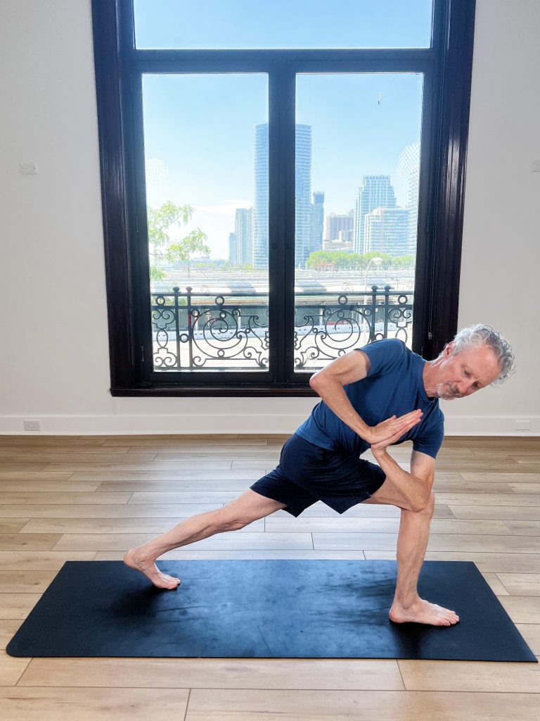 Man on a yoga mat doing revolved extended side angle