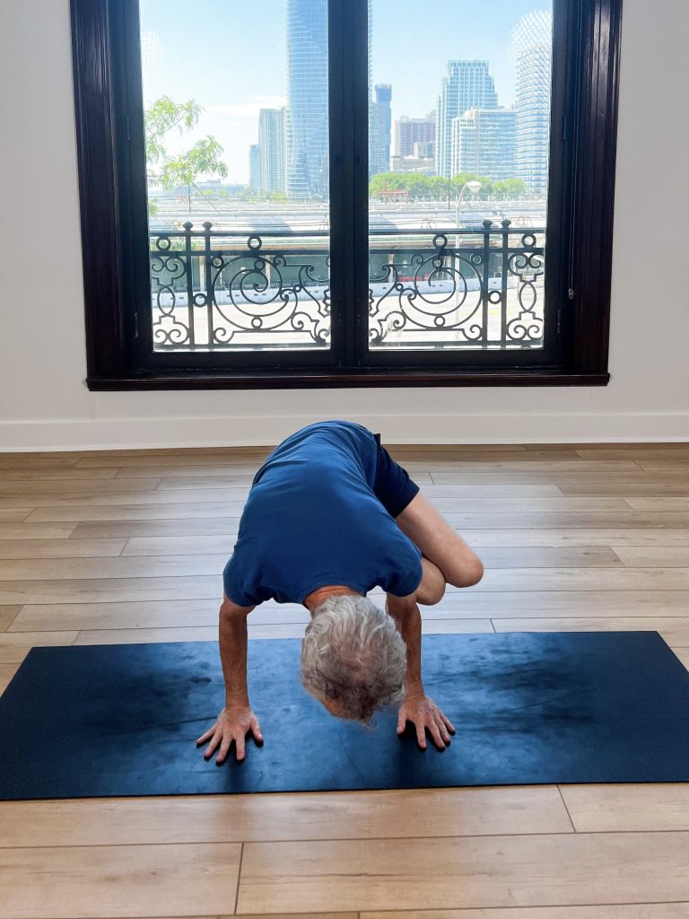 Man in side crow on a yoga mat