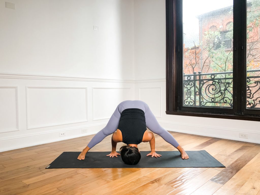 Girl in Wide Leg Forward Fold on yoga mat