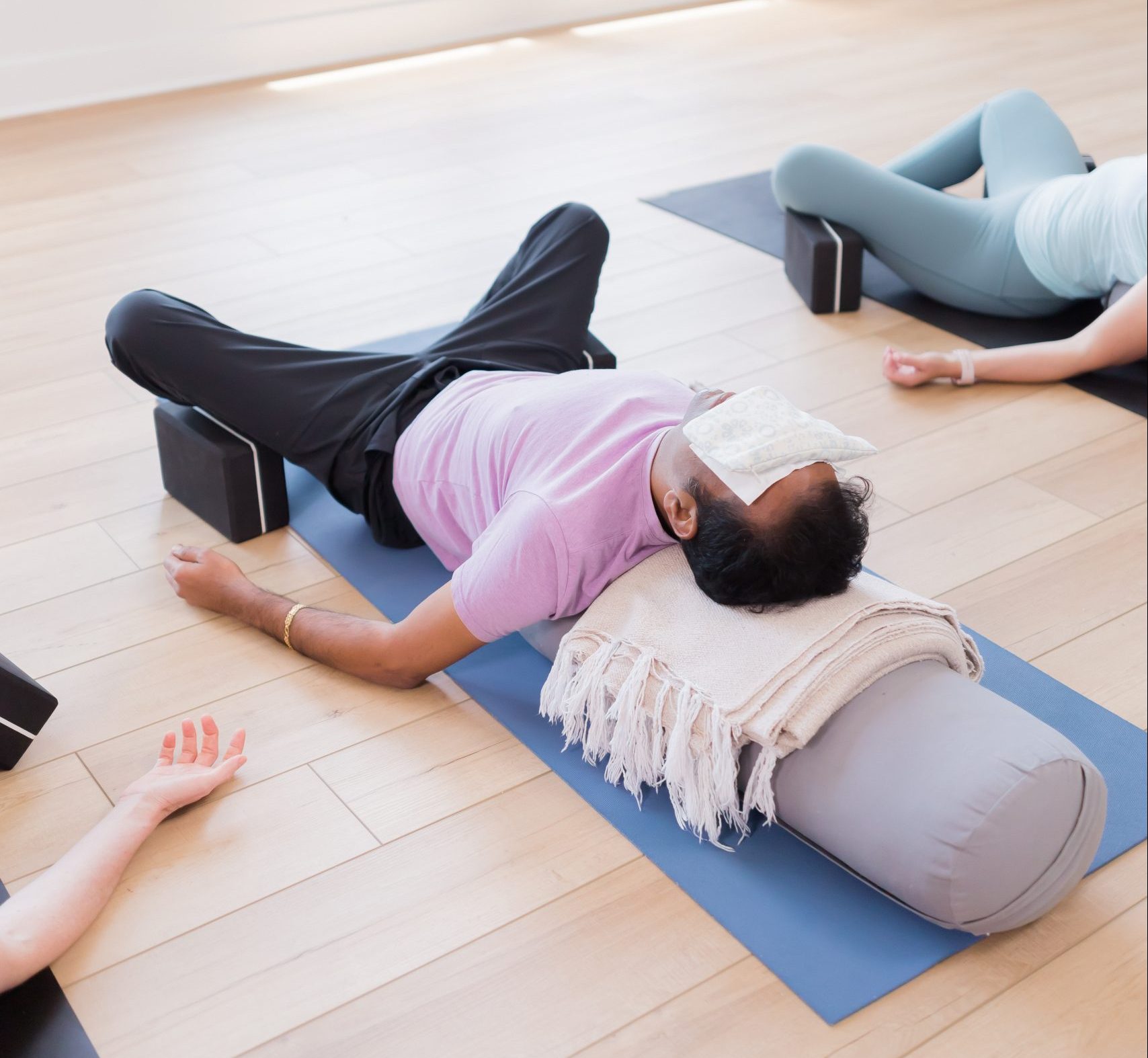 Yin students in savasana with eye pillows on