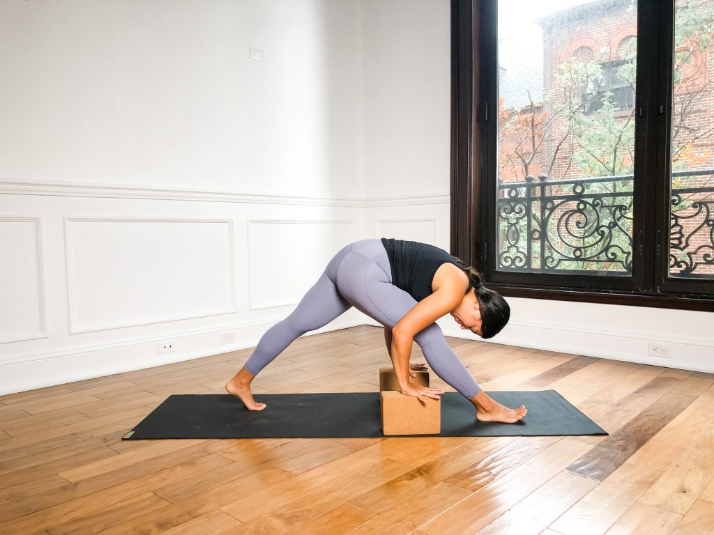 Yogi in Pyramid Pose (Parsvottanasana) on a black yoga mat using blocks under the hands