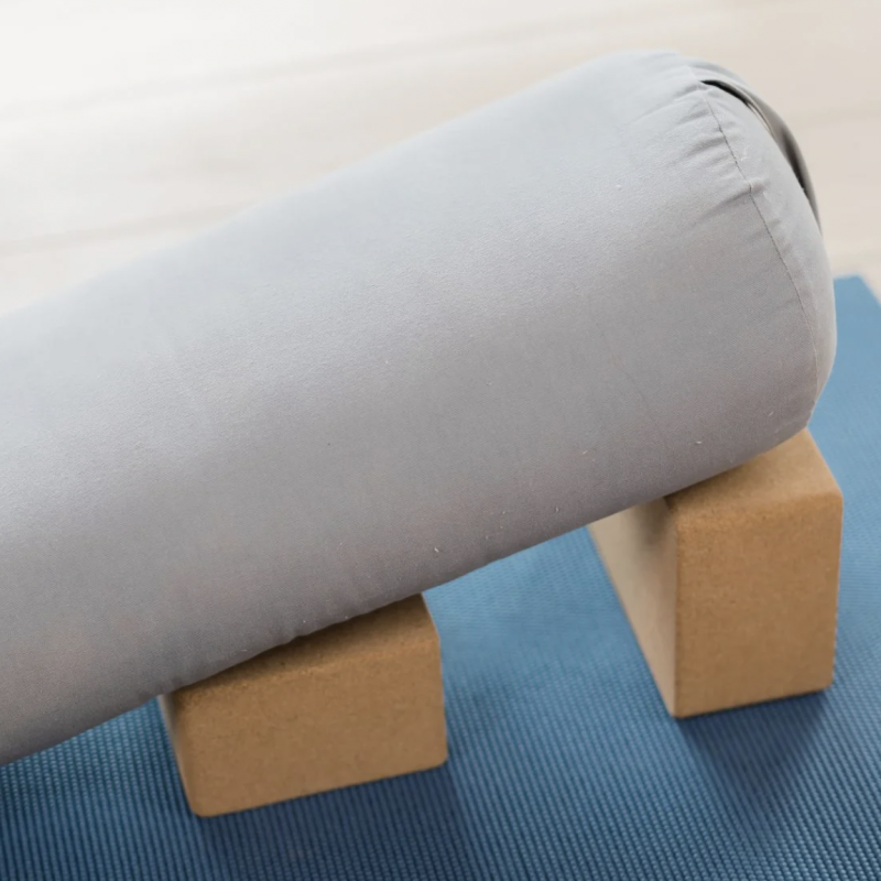 Yoga bolster resting on two blocks on top of a yoga mat