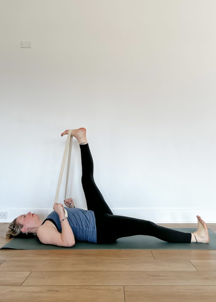 Woman in Utthita Hasta Padangusthasana (Extended Hand-to-Big-Toe Pose) Variation: Reclined with a Strap