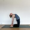 Human in Camel Pose on a green yoga mat