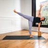 Person in Half Moon pose with their left hand on a block, right arm raised, on a black yoga mat
