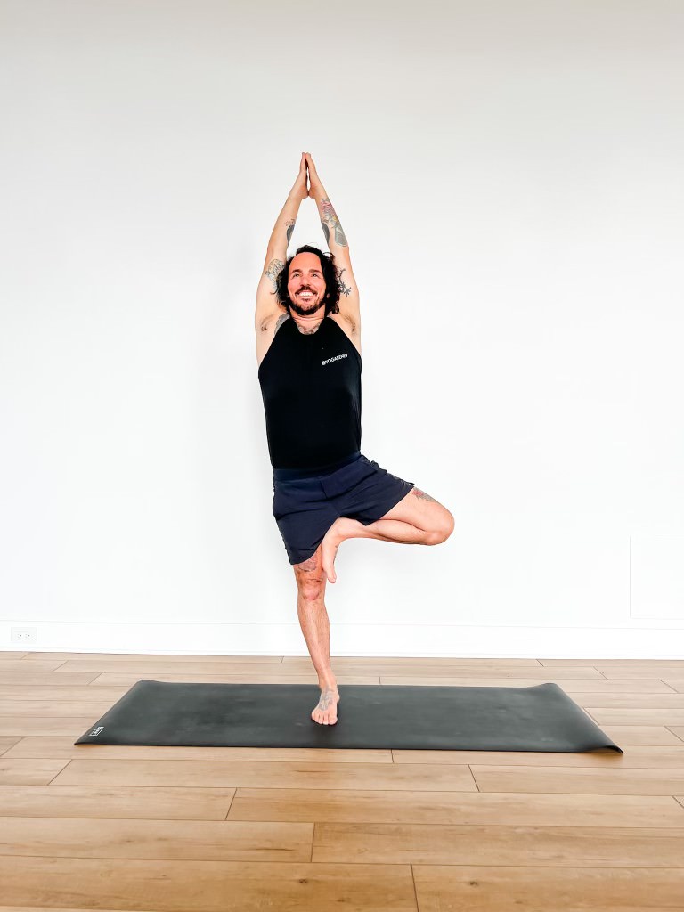 Patrick in tree pose on a yoga mat