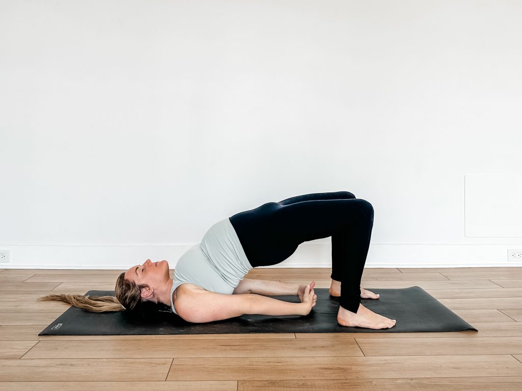 Woman on a black yoga mat doing bridge pose