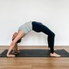 Woman in full wheel pose on a black yoga mat