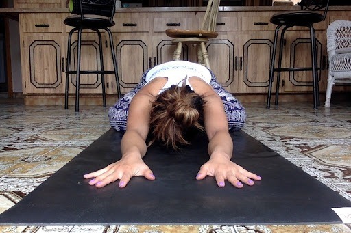 Mel Rodriguez in child's pose on a yoga mat in her 200 hour yoga teacher training