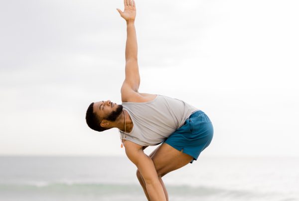 Black male yogi doing a side twist in chair pose