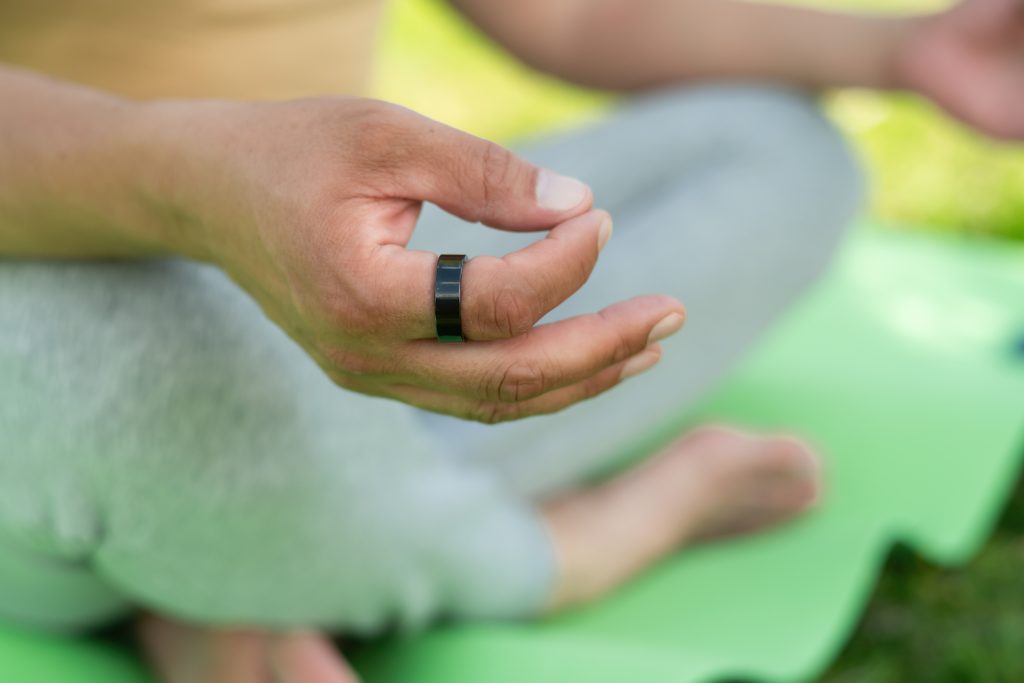 Closeup photo of a hand with a black health tracking ring on the first finger
