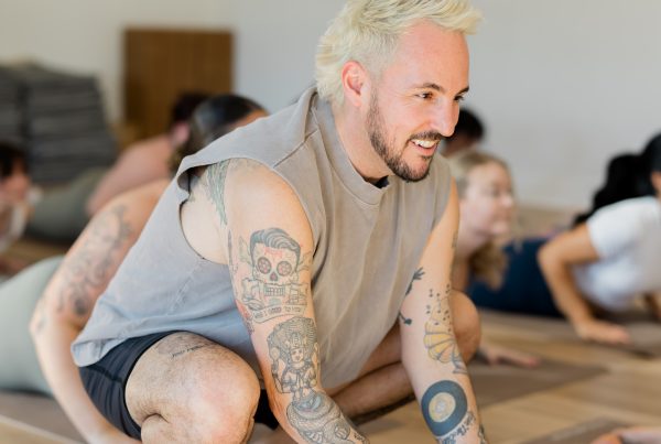 Patrick Franco giving a hands-on assist in cobra pose, touching the back of the calves