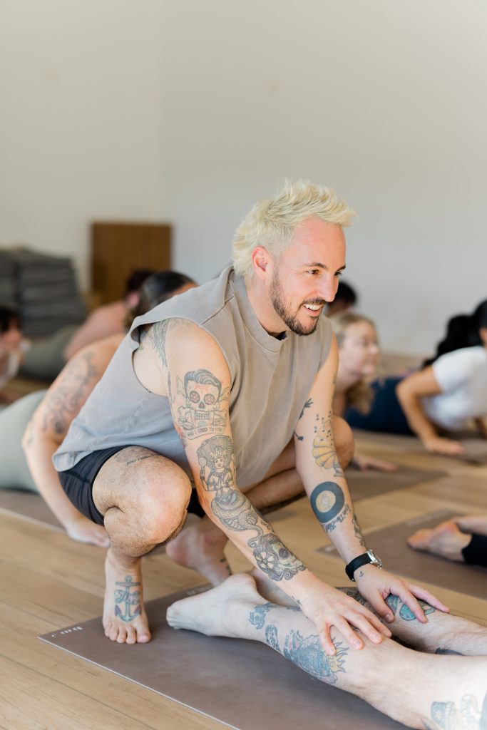 Patrick Franco giving a hands-on assist in cobra pose, touching the back of the calves