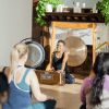 Julie Pasqual in front of a yoga class, playing the harmonium discussing the Manos in yoga philosophy