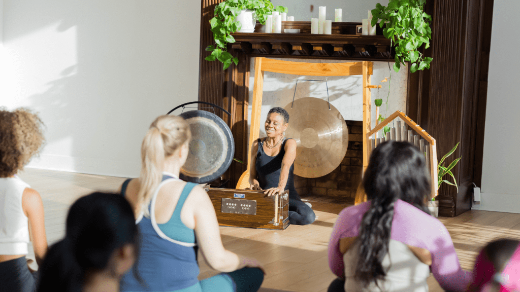 Julie Pasqual in front of a yoga class, playing the harmonium discussing the Manos in yoga philosophy