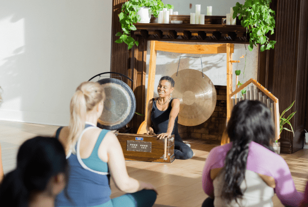 Julie Pasqual in front of a yoga class, playing the harmonium discussing the Manos in yoga philosophy