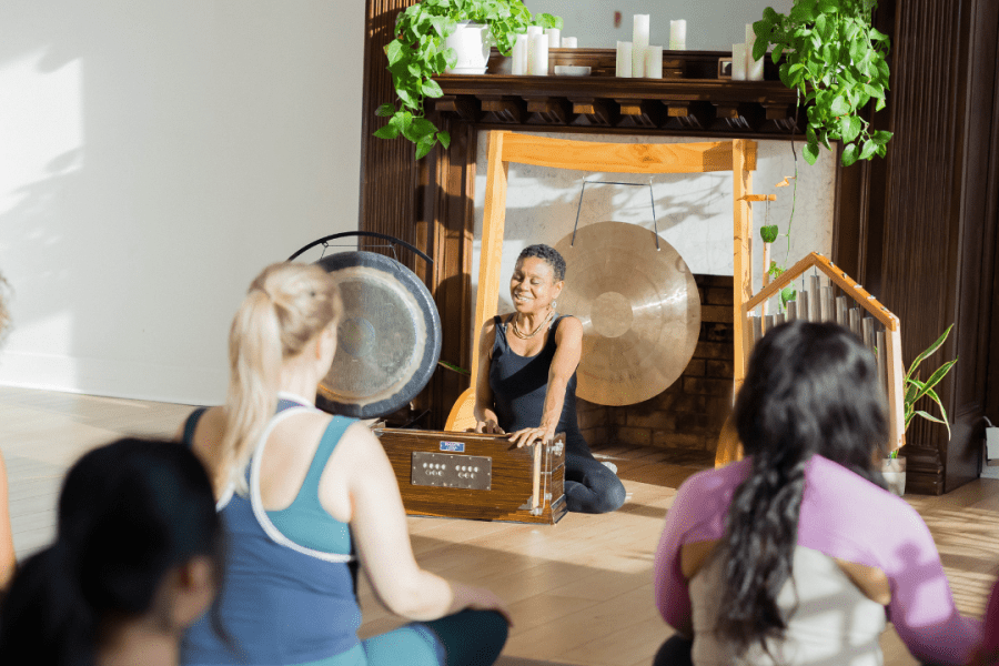 Julie Pasqual in front of a yoga class, playing the harmonium discussing the Manos in yoga philosophy