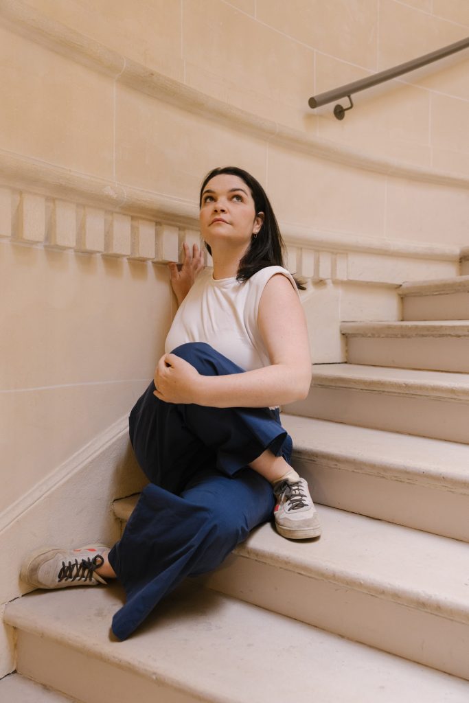 MƩlie Purdon sitting on a staircase in half Marichyasana