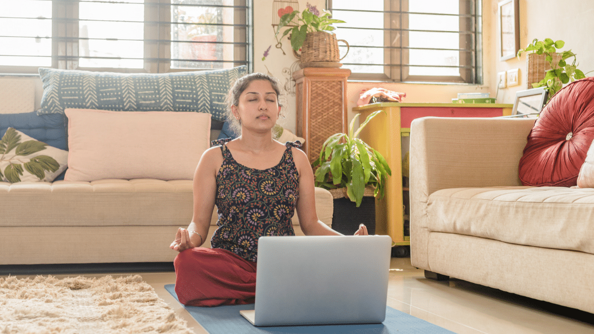 A woman taking our Breathwork & Pranayama Online Course, closing her eyes and breathing to study the anatomy of the breath and benefits of breathwork.
